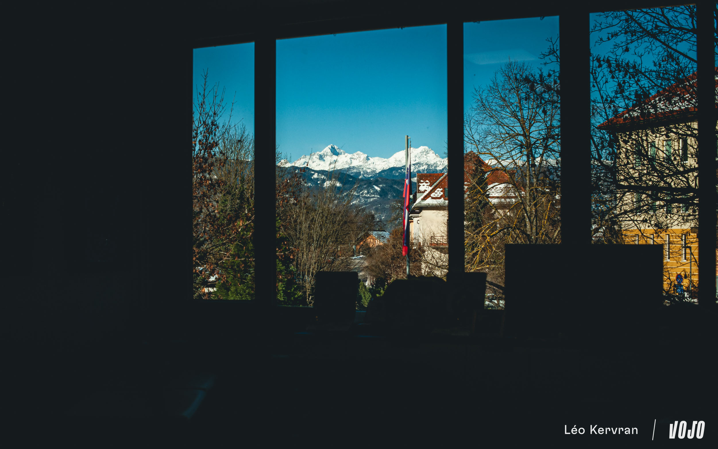 Drapeau national devant la fenêtre, Triglav qui domine le paysage en fond : bienvenue en Slovénie !